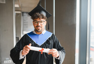 Happy arab student showing his university diploma at graduation ceremony Smiling arab student wearing a graduation gown and holding a diploma, celebrating academic achievement with pride and joy